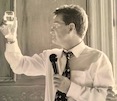 tiny image dad with mic and raising a champagne glass for a toast